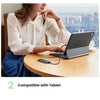 A woman is using a black tablet connected to a USB-C hub on a wooden table.