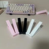 A collection of pink and white ergonomic keyboard height adjuster stands and a purple mechanical keyboard.