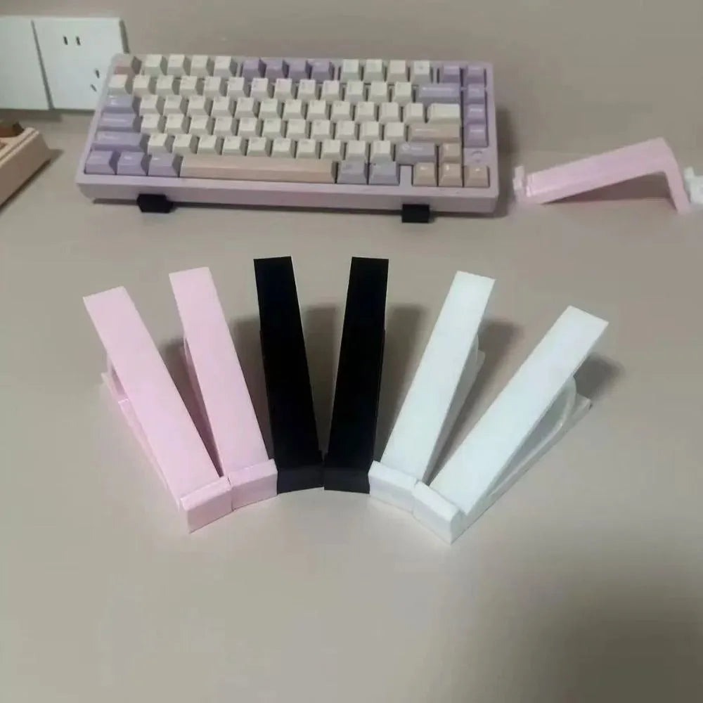 A collection of pink and white ergonomic keyboard height adjuster stands and a purple mechanical keyboard.