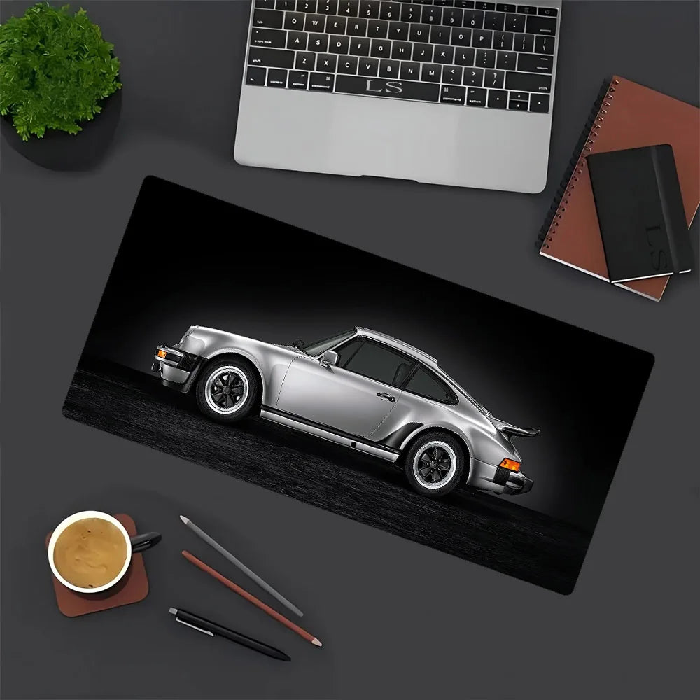 A silver JDM car is displayed on a black mouse pad next to a laptop and writing tools.