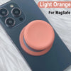 A light orange silicone cover for a MagSafe phone grip stand on a dark blue smartphone.