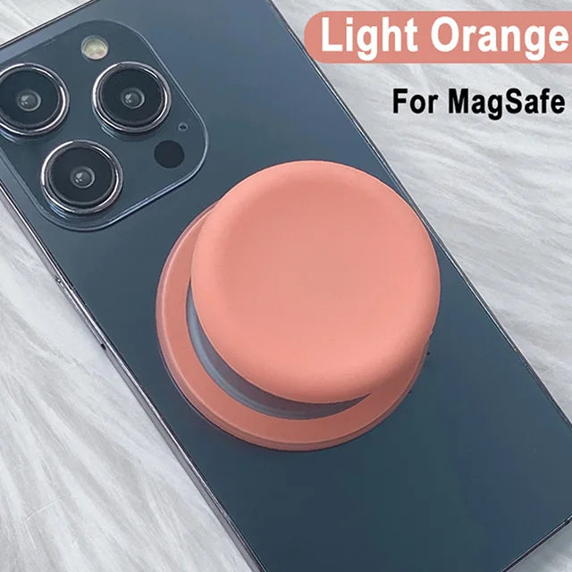 A light orange silicone cover for a MagSafe phone grip stand on a dark blue smartphone.