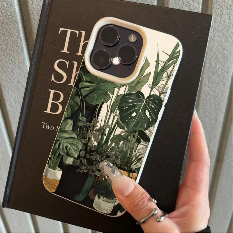 Eine Hand hält eine Handyhülle mit grünem Monstera-Blattmuster auf schwarzem Hintergrund.