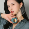 A woman is using a portable mini blade-less electric fan, which is a small, round device with a translucent casing.