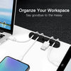 A silicone cable organizer set with multiple white cables and a USB plug is shown on a laptop workspace.