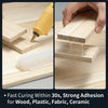 A hand applies a hot melt glue stick to a piece of wood, demonstrating strong adhesion for various materials.