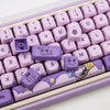 A close-up view of a purple Magic Bunny PBT keycap set with various characters and symbols on a light pink keyboard tray.