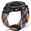Eine schwarze Smartwatch mit rundem Zifferblatt und farbigem gewebtem Armband am Handgelenk.