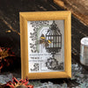 A wooden frame holds a decorative silver stamping lace tape featuring botanical designs and a birdcage silhouette.