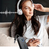 Eine Frau benutzt einen schwarzen Ugreen Bluetooth-Adapter, um Musik zu hören und gleichzeitig auf ihr Smartphone zu schauen.