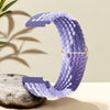 A purple nylon watch strap is shown curved, resting on a gray stone.