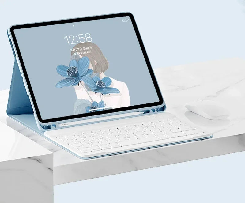 A silver magnetic keyboard case for an iPad Pro is shown open on a white marble surface.