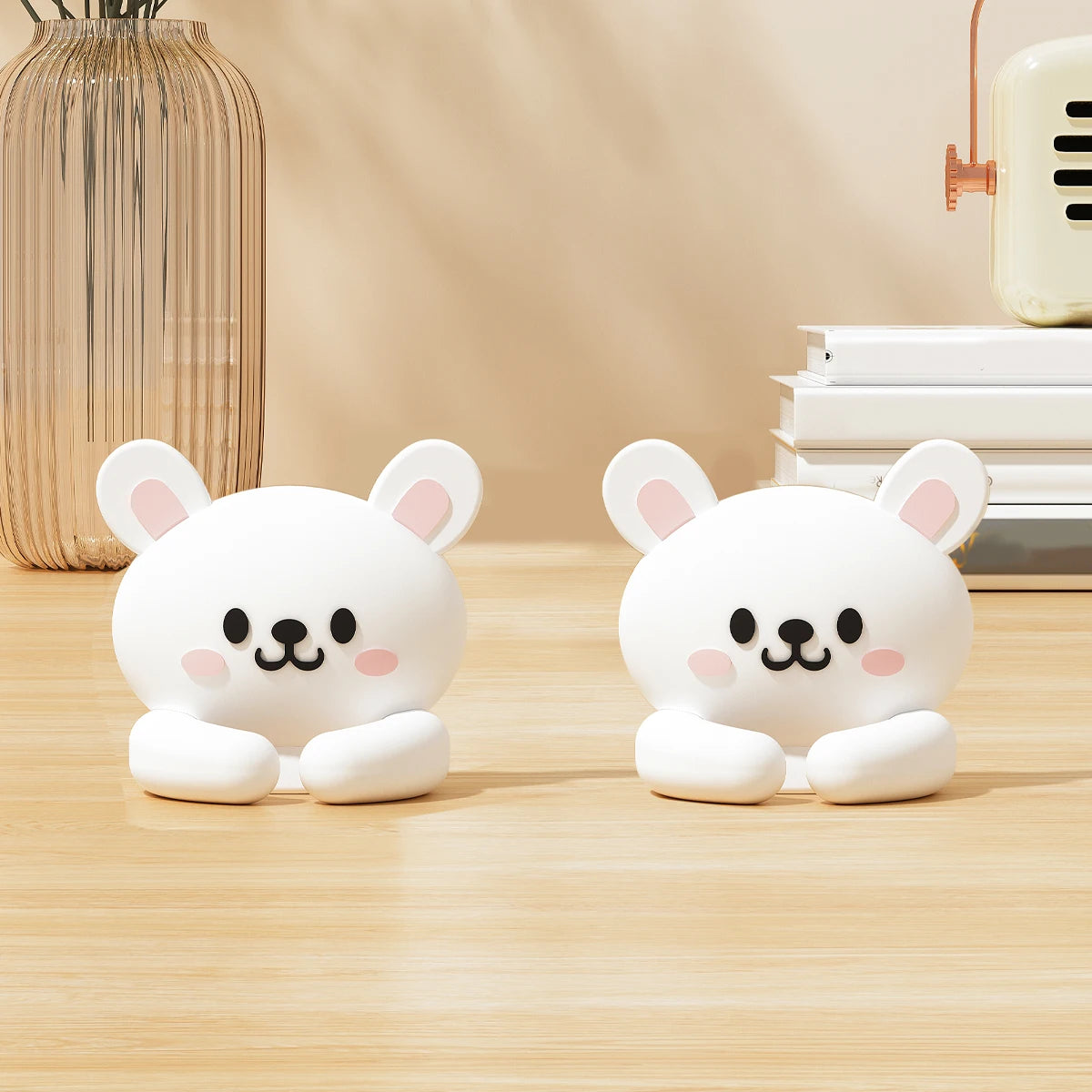 Two white cartoon bear desk cable organizers sitting on a wooden surface.