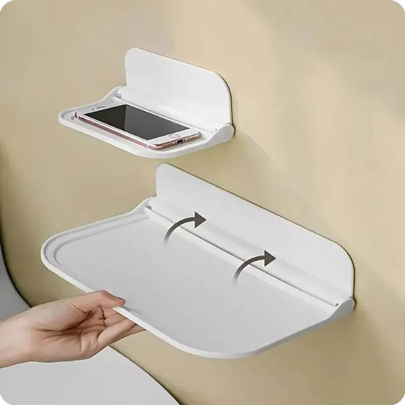 A white foldable wall shelf with a hinged lid is shown, displaying a smartphone inside for storage.