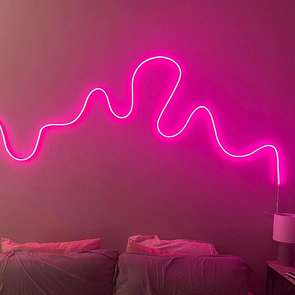 Una luz de neón rosa con forma de línea ondulada ilumina una pared en un dormitorio.