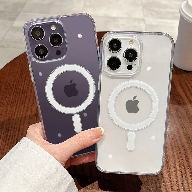A hand holds two magnetic transparent phone cases, one purple and one clear, on a wooden surface.