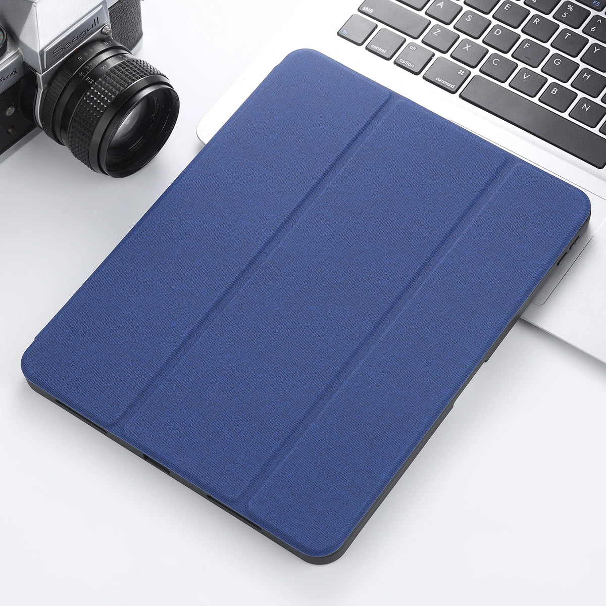 A dark blue retro marbling skin for an iPad Pro placed next to a silver camera and a white laptop keyboard.