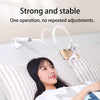 A woman is using a flexible gooseneck phone clamp mount attached to a bed for hands-free operation.