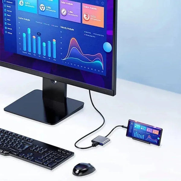 A computer monitor displaying financial analysis charts next to a keyboard, mouse, and a small USB-C to HDMI docking adapter.