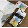 A collection of colorful decorative bookmarks and paper clips in various shapes and colors are displayed on a brown surface.