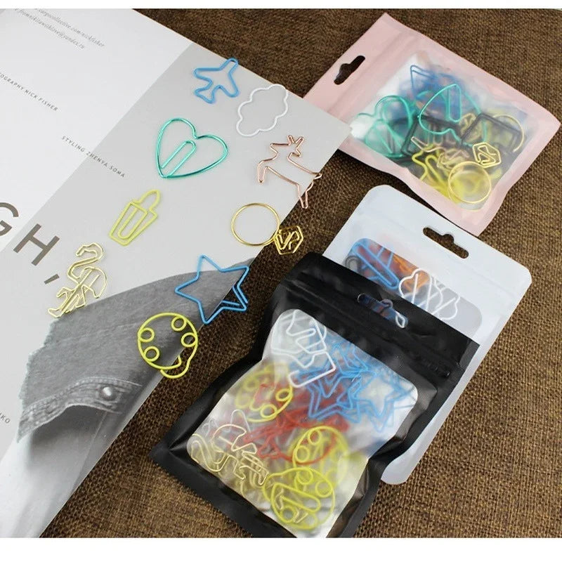 A collection of colorful decorative bookmarks and paper clips in various shapes and colors are displayed on a brown surface.