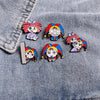 A set of five colorful cartoon anime brooches pinned on a denim fabric.