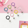 A collection of colorful clear acrylic card holders with metal keychains arranged on a pink and white background.
