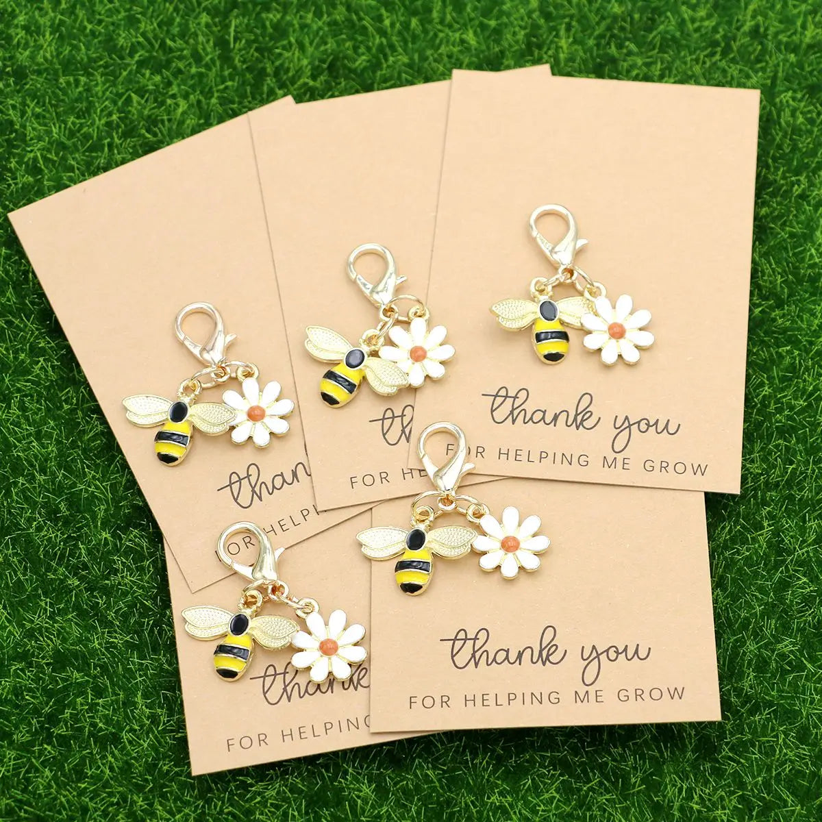 Five small yellow and black ladybug and daisy keychains are displayed on light brown cards.