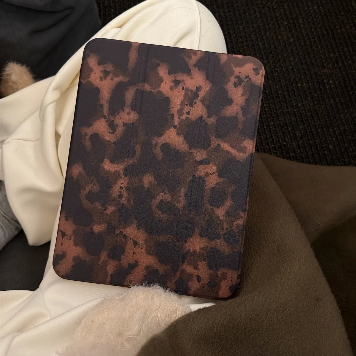 Dunkelbraunes Leopardenmuster-Leder-Tablet-Cover auf dunklem Stoff