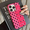 A pink polka dot phone case with a clear back and silver nail polish is held against a dark box.