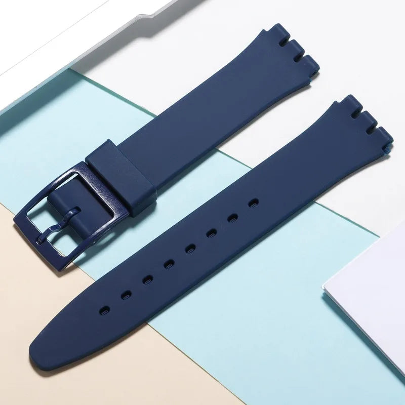 A dark blue silicone watch strap is shown alongside replacement tools on a light background.