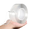 A hand holds a roll of heavy duty clear double-sided gap tape, showing the transparent adhesive tape and its packaging.