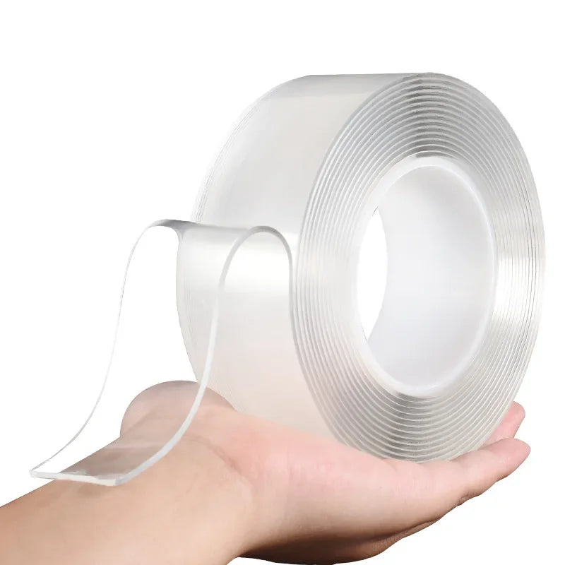 A hand holds a roll of heavy duty clear double-sided gap tape, showing the transparent adhesive tape and its packaging.
