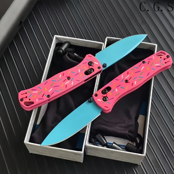 Pink donut acrylic folding knife with a blue steel blade displayed in a box.