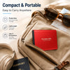 Rote tragbare SSD in einer beigen Stofftasche zusammen mit Sonnenbrille und Reisepass
