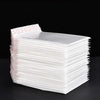 Pile de pochettes blanches rembourrées de qualité pour l'expédition et les cadeaux, avec une étiquette.
