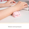 Pink piggy shaped ergonomic wrist rest placed on a white desk next to hands typing on a computer.