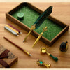 A luxury fountain pen set with a dark green feather pen and gold accents displayed in a wooden box.