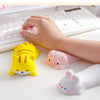 A hand rests on a white keyboard with a yellow cat and a pink pig shaped ergonomic wrist rest nearby.