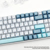 A close-up view of a set of light blue and gray PBT keycaps for mechanical keyboards.