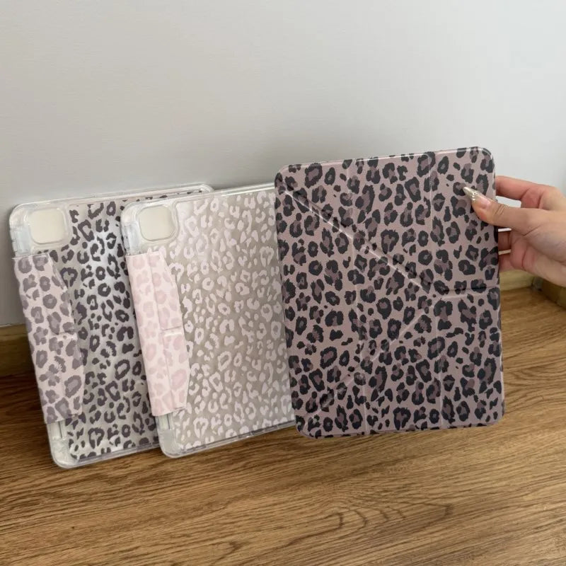 A hand holds a stack of leopard print leather cases for an iPad, featuring various shades and patterns.