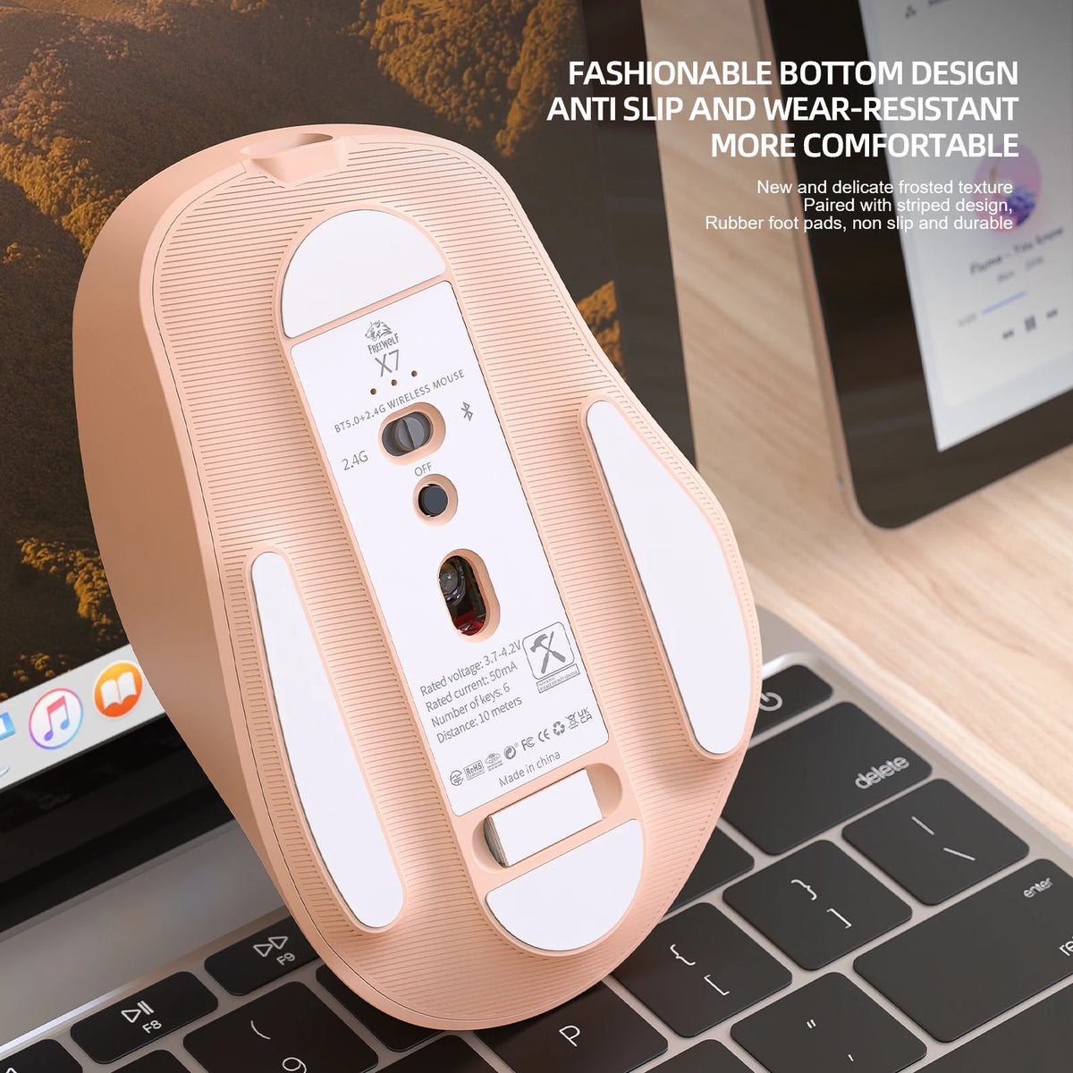 A peach-colored wireless mouse with a textured bottom design is shown resting on a laptop keyboard.