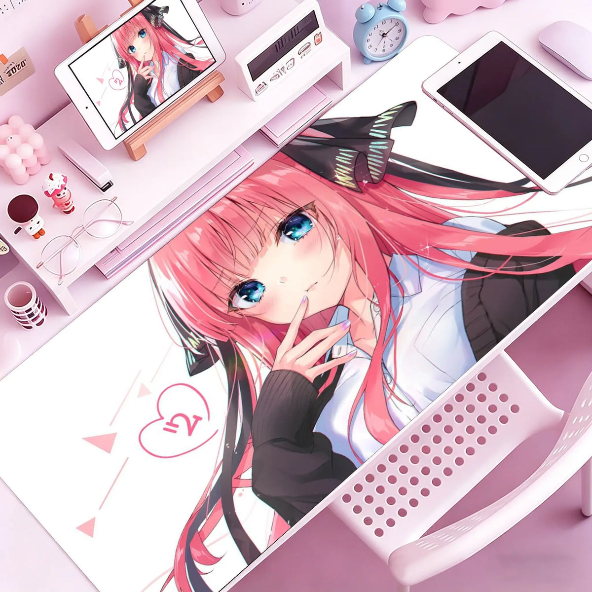A close-up of an anime-style illustration featuring a pink-haired girl, surrounded by various stationery and tech accessories