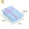 A light blue jewelry gift box with a purple ribbon, shown from above and side view.