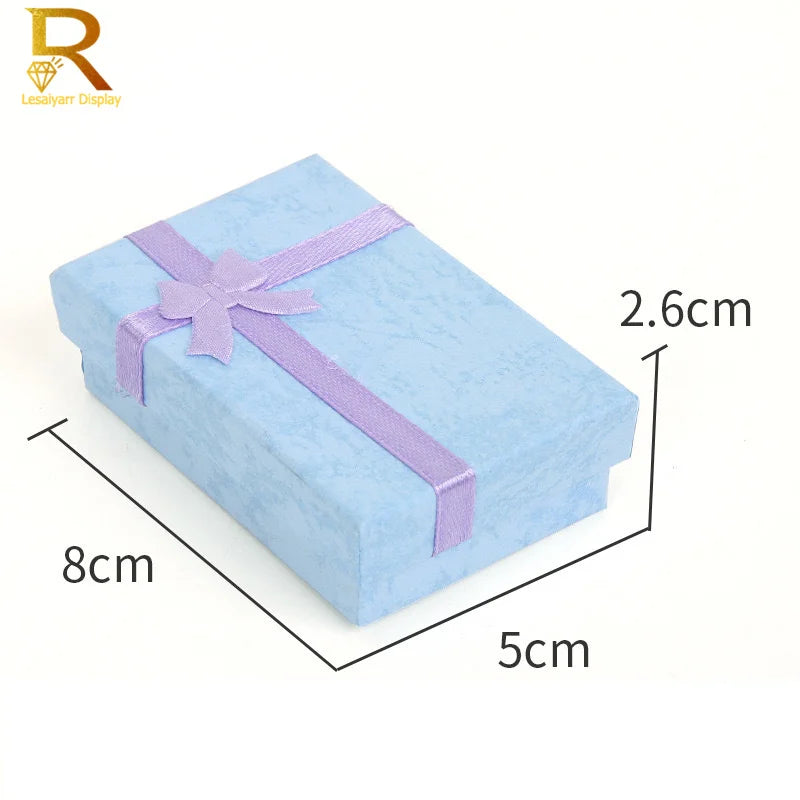 A light blue jewelry gift box with a purple ribbon, shown from above and side view.