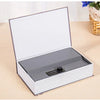 A silver and white mini secret cash storage box with a lid open, resting on a light wooden surface.