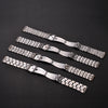 A collection of stainless steel watch bands with folding safety clasps laid diagonally on a dark surface.