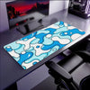 A blue wave art non-slip mouse pad with a lockedge is displayed on a dark desk next to a computer monitor.
