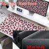 A black desk mat with a leopard print design is shown next to a digital clock and other office supplies.