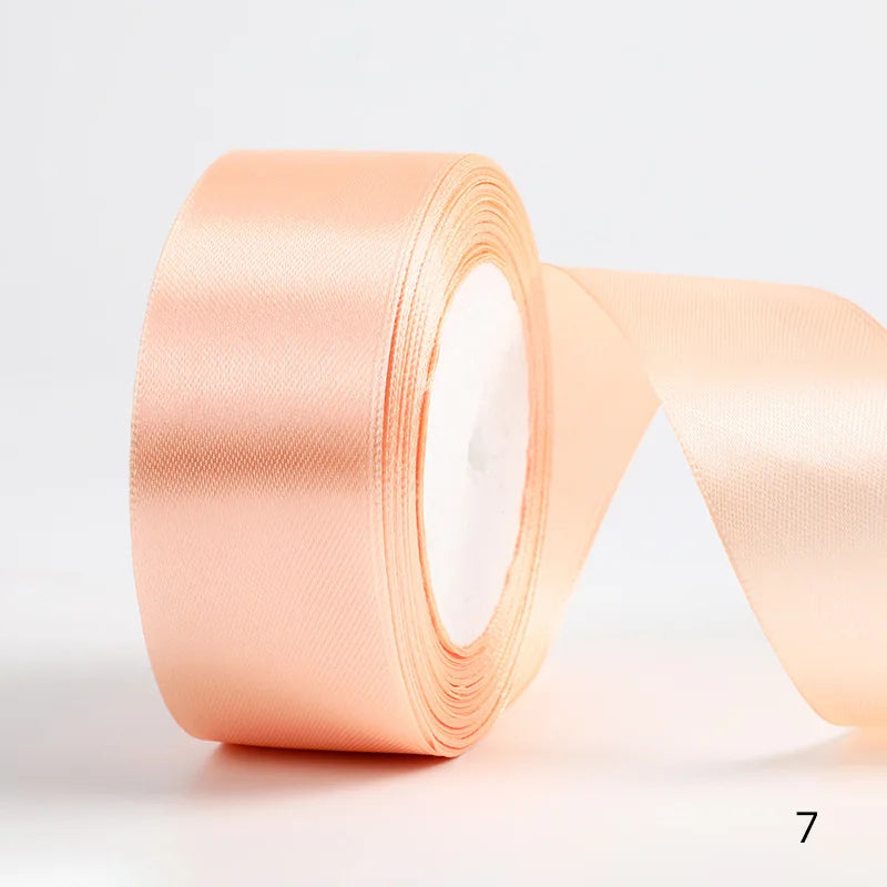 A roll of peach-colored satin ribbon for gift wrapping and DIY crafts.